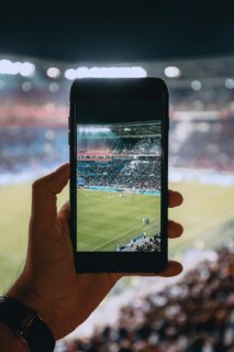 Spectator using a smartphone during a football match, illustrating mobile betting